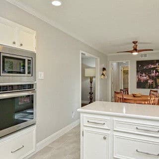 Modern kitchen with white cabinetry, stainless steel appliances, and a dining area.