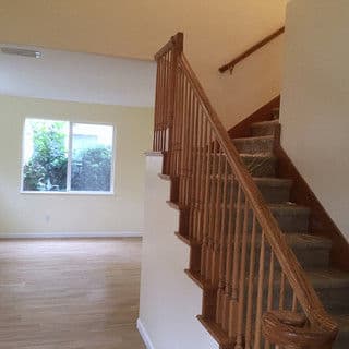 Interior view of a home featuring a staircase, light-colored walls, and a large window.