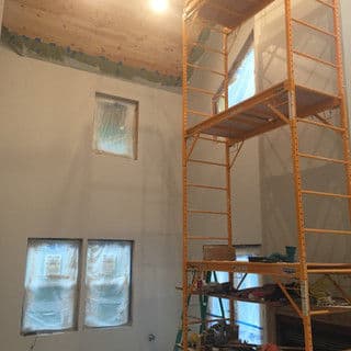 Interior of a room under renovation, featuring scaffolding and covered windows.