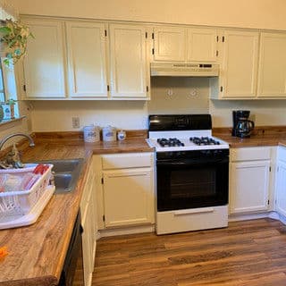 Modern kitchen with white cabinetry, a gas stove, and wooden countertops. Bright and functional space.