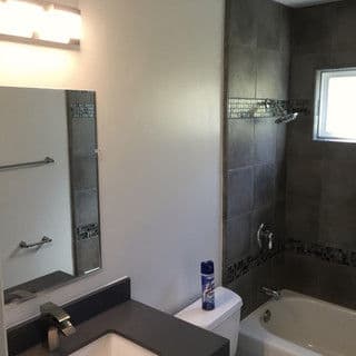 Modern bathroom featuring a shower, bathtub, sink, and mirror with natural light.