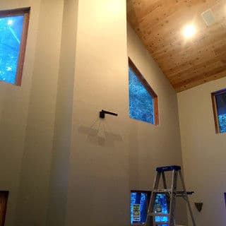 Interior of a modern home with wood ceiling, tall walls, and a ladder against the wall.