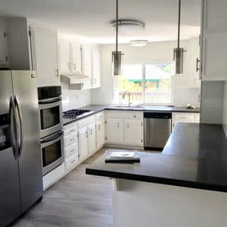 Modern kitchen with white cabinets, stainless steel appliances, and gray countertops.