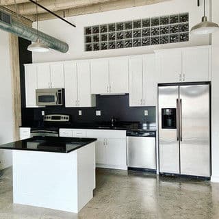 Modern kitchen with white cabinets, stainless steel appliances, and a black countertop.