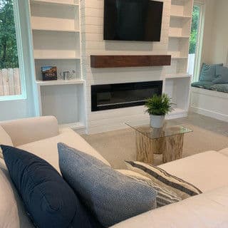 Modern living room with white couch, wood accents, and a minimalist fireplace.