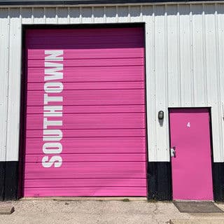 Pink warehouse door with "SOUTHTOWN" printed in large white letters and a small side door.