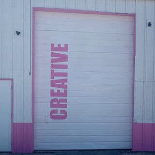 Pink and white garage door with the word "CREATIVE" prominently displayed.